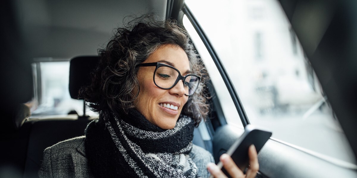 woman traveling by car, looking at phone